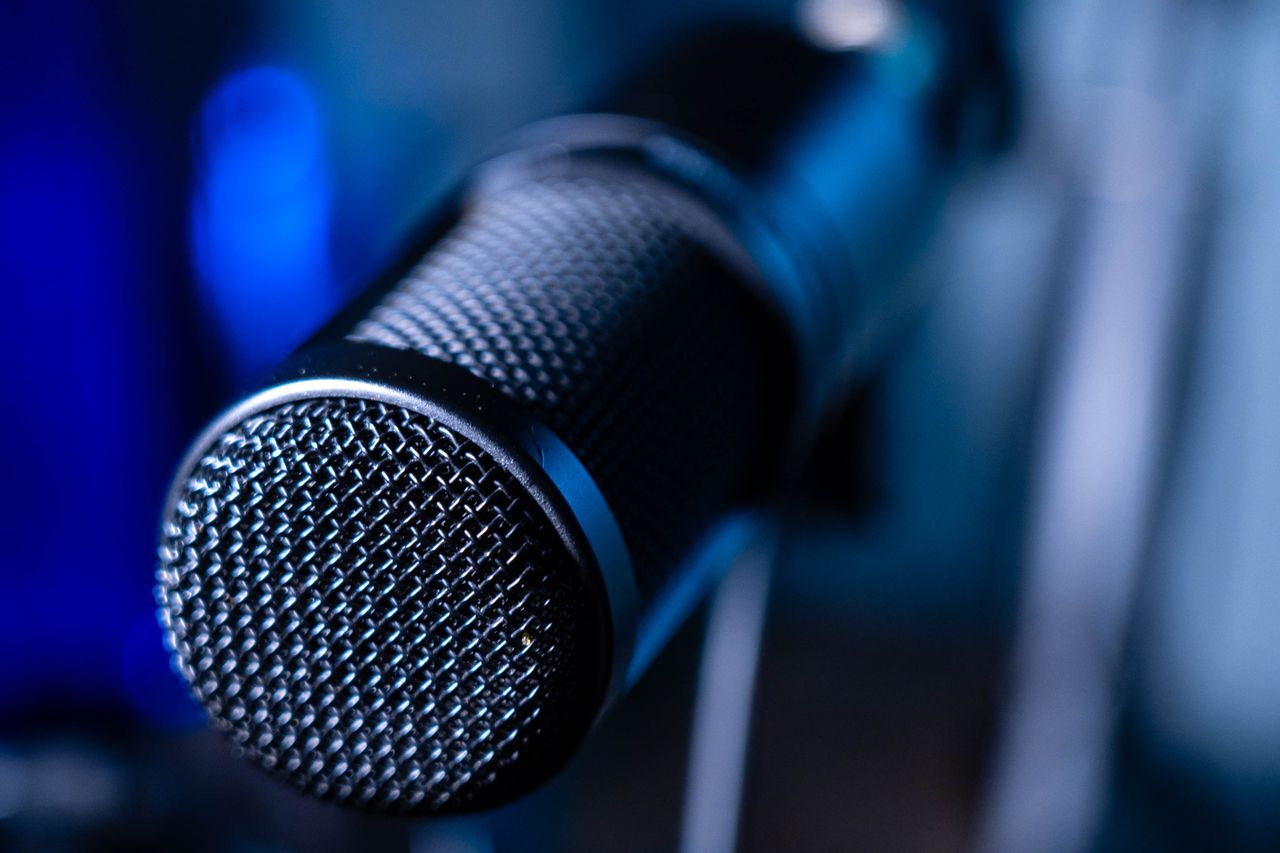 Detailed close-up of a professional studio microphone with a blurred blue background.